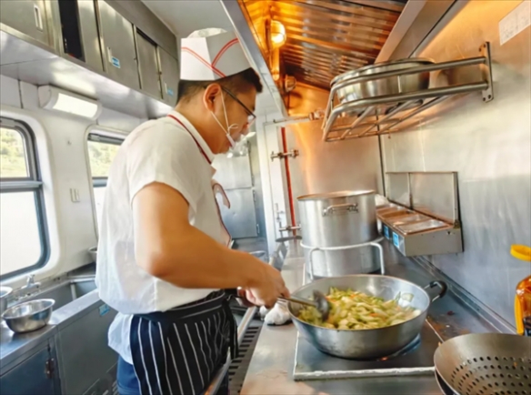 近年来，绿皮火车上的菜肴因现场炒制频登热搜榜单！厨师们在摇晃的列车上熟练掌勺，展现绝技。  
